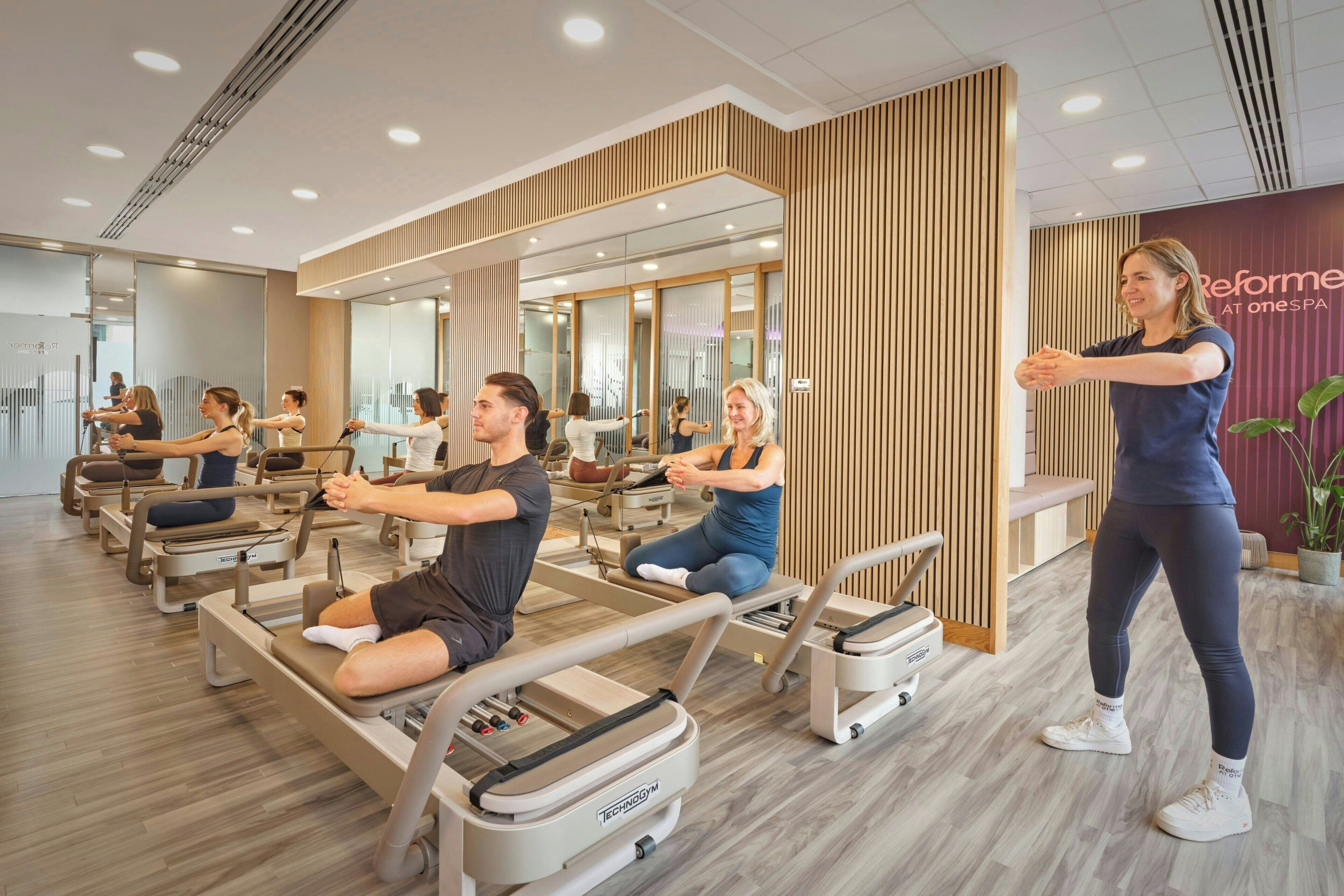 Un estudio de Pilates con equipo, espejos y una pared de madera.
