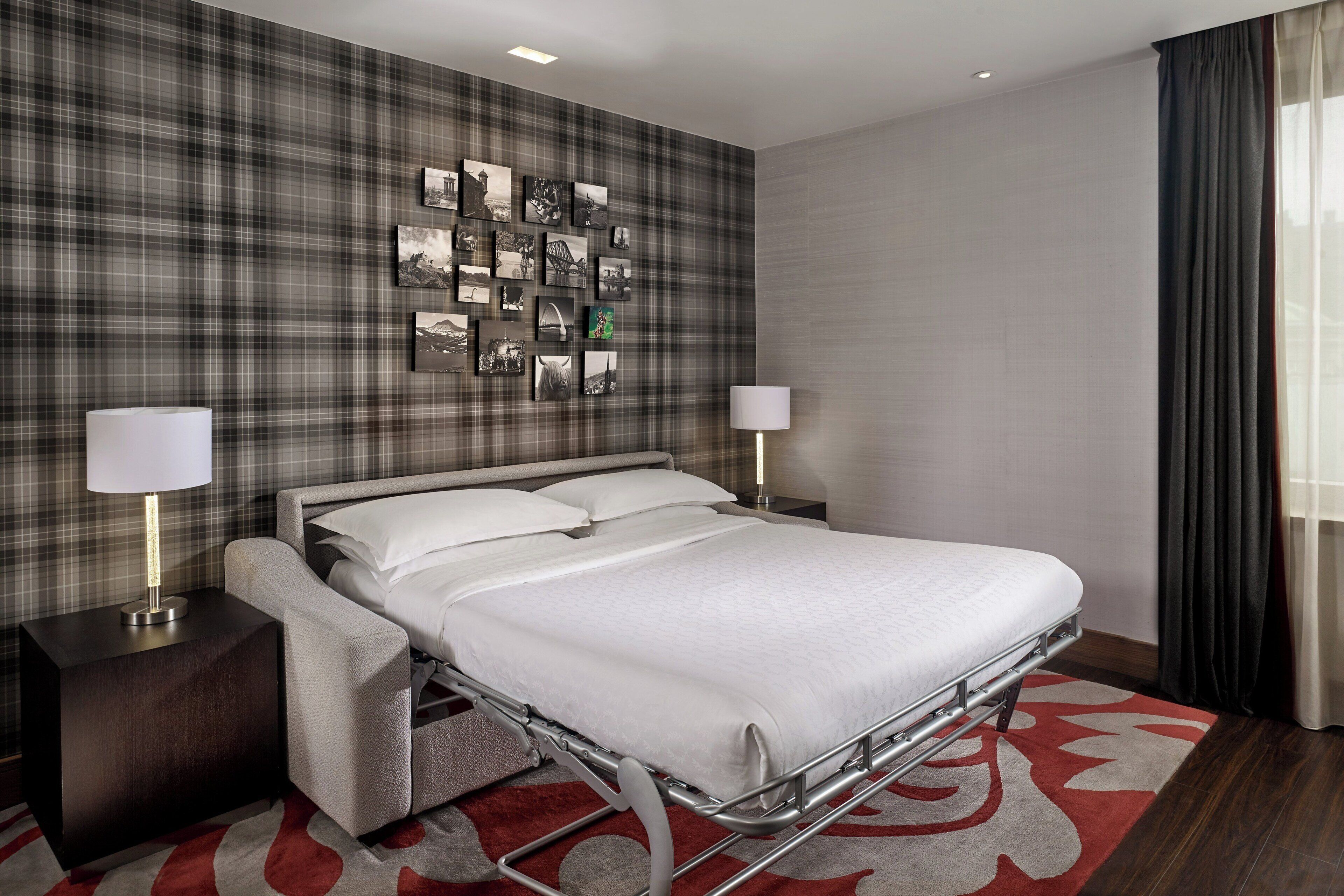 A hotel room with a bed, bedside tables, a wall-mounted picture gallery, and a window with curtains.