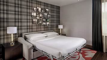A hotel room with a bed, bedside tables, a wall-mounted picture gallery, and a window with curtains.
