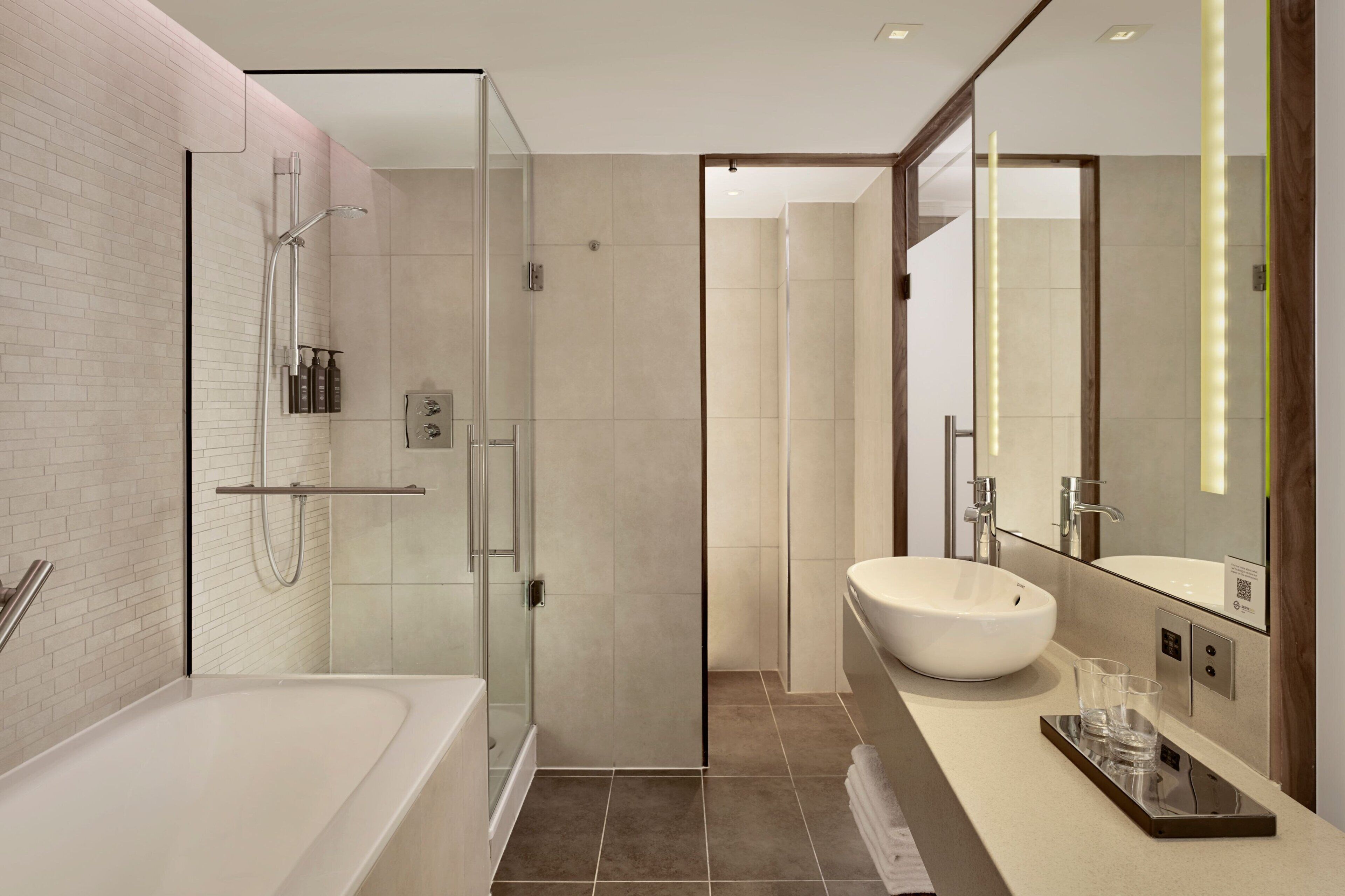 Een moderne badkamer met een douchecabine van glas, een ruim bad en een wastafel met een grote spiegel.
