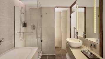 A modern bathroom with a glass-enclosed shower, a large bathtub, and a vanity with a large mirror.