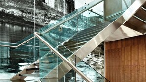 A modern staircase with glass railings and a red seating area.