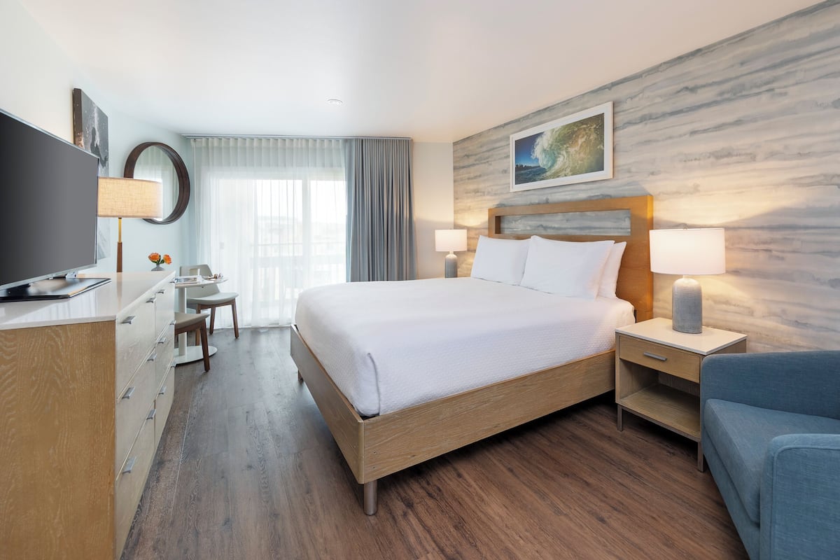 Une chambre d’hôtel avec un grand lit, des tables de chevet, un bureau, une chaise et un téléviseur.