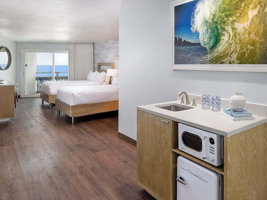 Une chambre d’hôtel avec un lit, un bureau, une petite kitchenette et une vue sur l’océan.