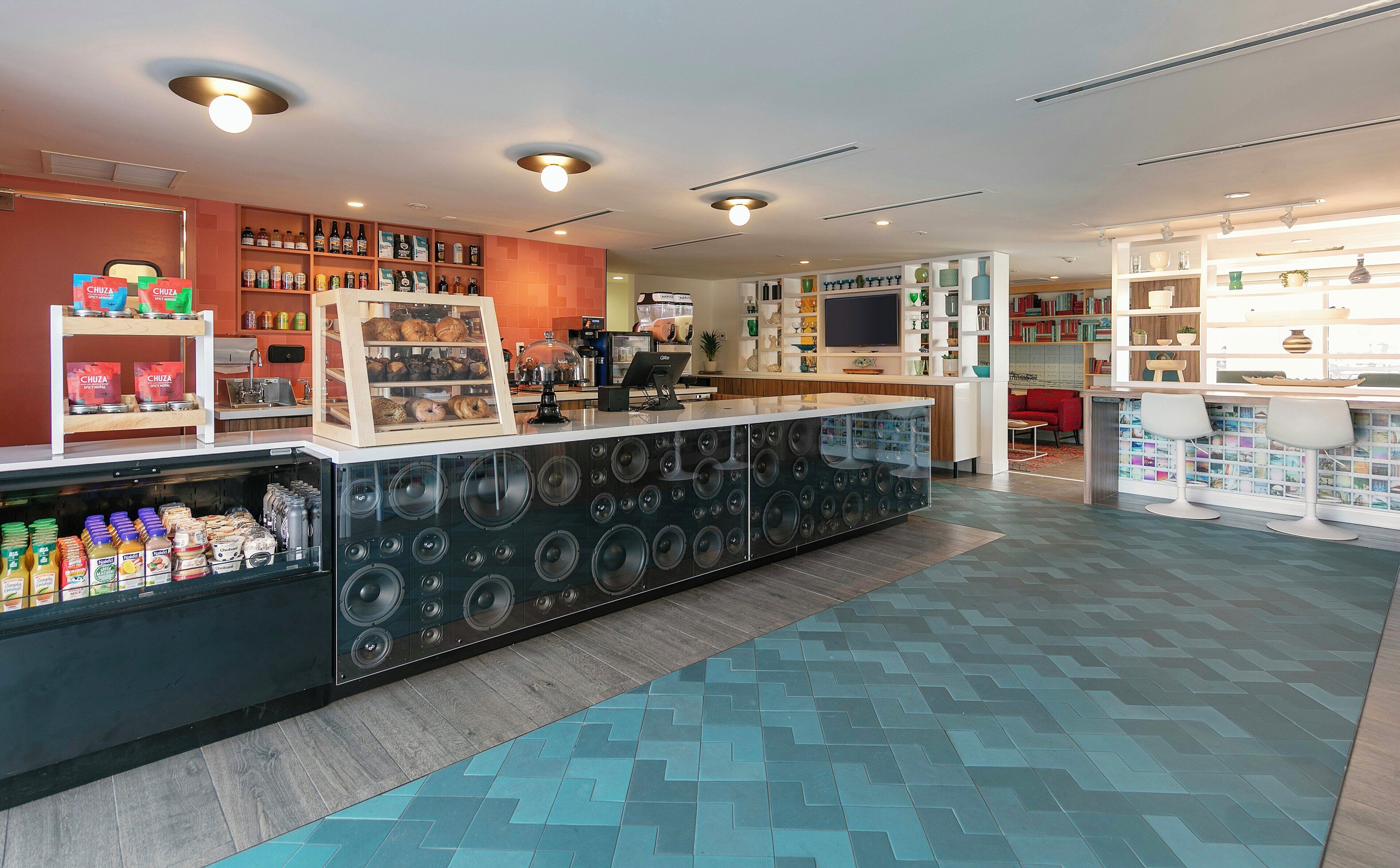A modern interior with a central counter, shelves with various items, and a patterned floor.