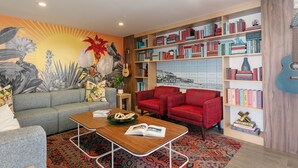 A living room with a grey sofa, red armchairs, a wooden coffee table, and a bookshelf filled with books. - The Wayfarer San Diego (San Diego)