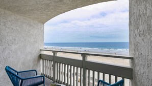 A balcony with a view of the beach, two blue chairs, a small table, and a potted plant. - The Wayfarer San Diego (San Diego)