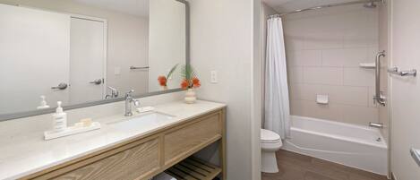 A modern bathroom with a wooden vanity, a large mirror, a shower with a curtain, and a toilet.