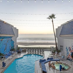Relax by the ocean-view pool surrounded by lounge chairs and sunbeds, with string lights overhead.