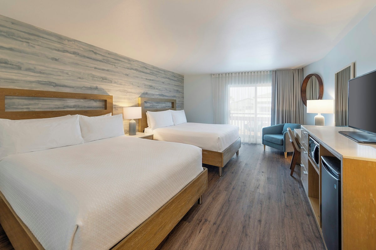 Une chambre d’hôtel avec deux lits, un bureau, une chaise, une télévision et un coin repas.