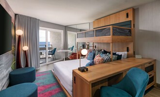 Una habitación de hotel moderna con una litera, un escritorio y un balcón con vistas al mar.