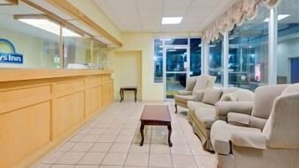 A reception area with a counter, a bench, and a seating area with sofas. - Days Inn by Wyndham Waynesboro (Waynesboro)