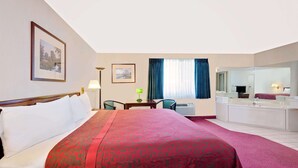A hotel room with a large bed, a desk, a chair, a bathroom with a sink and mirror, and two framed pictures on the wall. - Days Inn by Wyndham Waynesboro (Waynesboro)