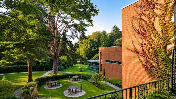 A courtyard with a brick building, outdoor seating, and trees. - Macdonald Berystede Hotel & Spa (Ascot)