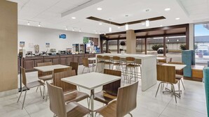 Un restaurant moderne doté de nombreuses tables et chaises, d’un comptoir où est affiché le menu, et offrant une vue sur l’extérieur.