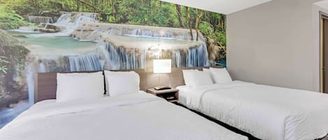 Habitación de hotel con dos camas, una mesita de noche y un mural de una cascada.
