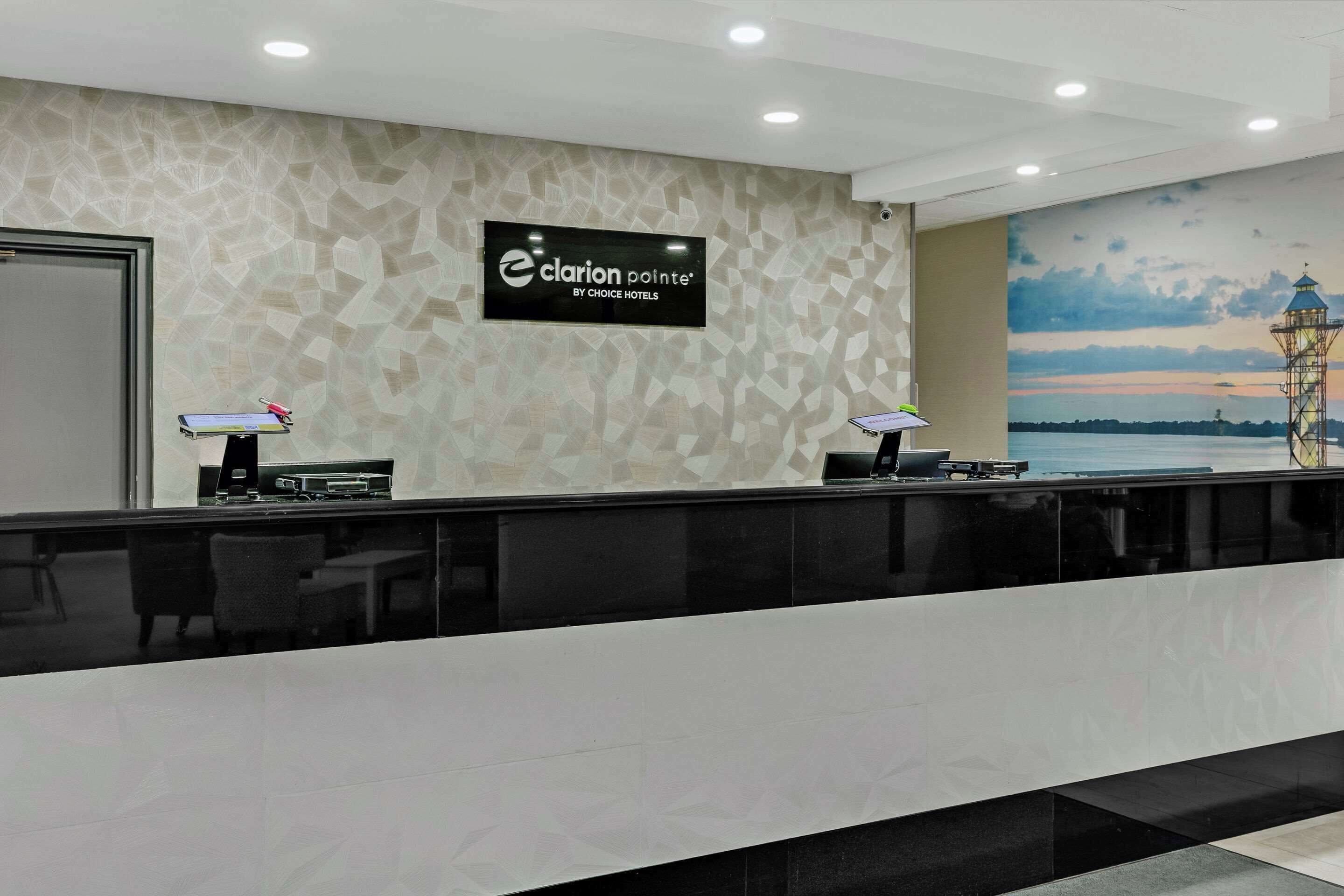 Un mostrador de recepción de diseño moderno, un reloj de pared grande y un mural con un faro.