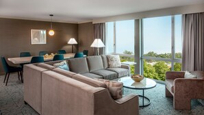 Une chambre d’hôtel moderne dotée d’une grande fenêtre, d’un canapé, d’une table à manger avec des chaises et d’une table basse.