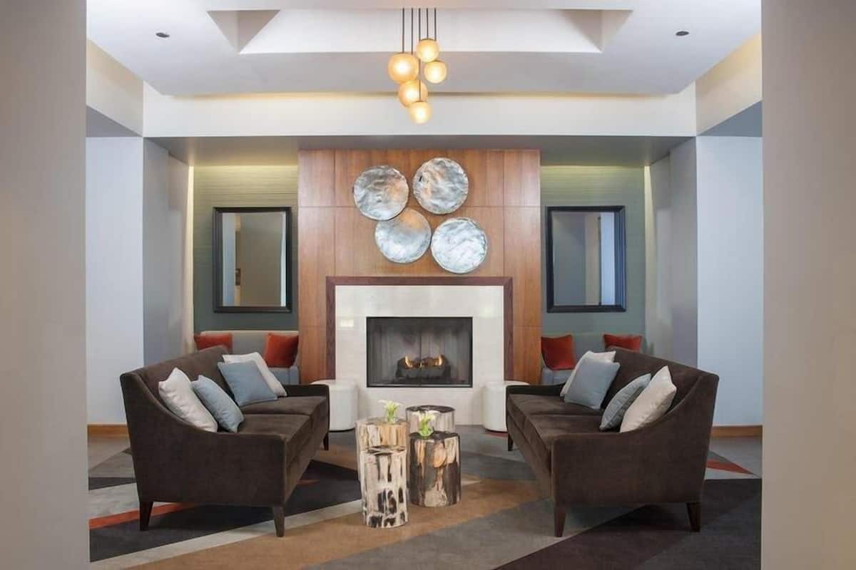 A modern living room with two sofas, a fireplace, and a wall-mounted art piece.