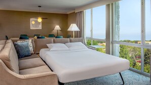 Une chambre d’hôtel avec un grand lit, un canapé, deux lampes et une vue sur l’extérieur.