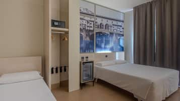 Habitación de hotel con dos camas, una mesita de noche pequeña, un armario y un ventanal con vista a un puente.