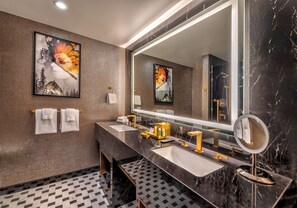 A modern bathroom with two sinks, a large mirror, and artwork on the walls.