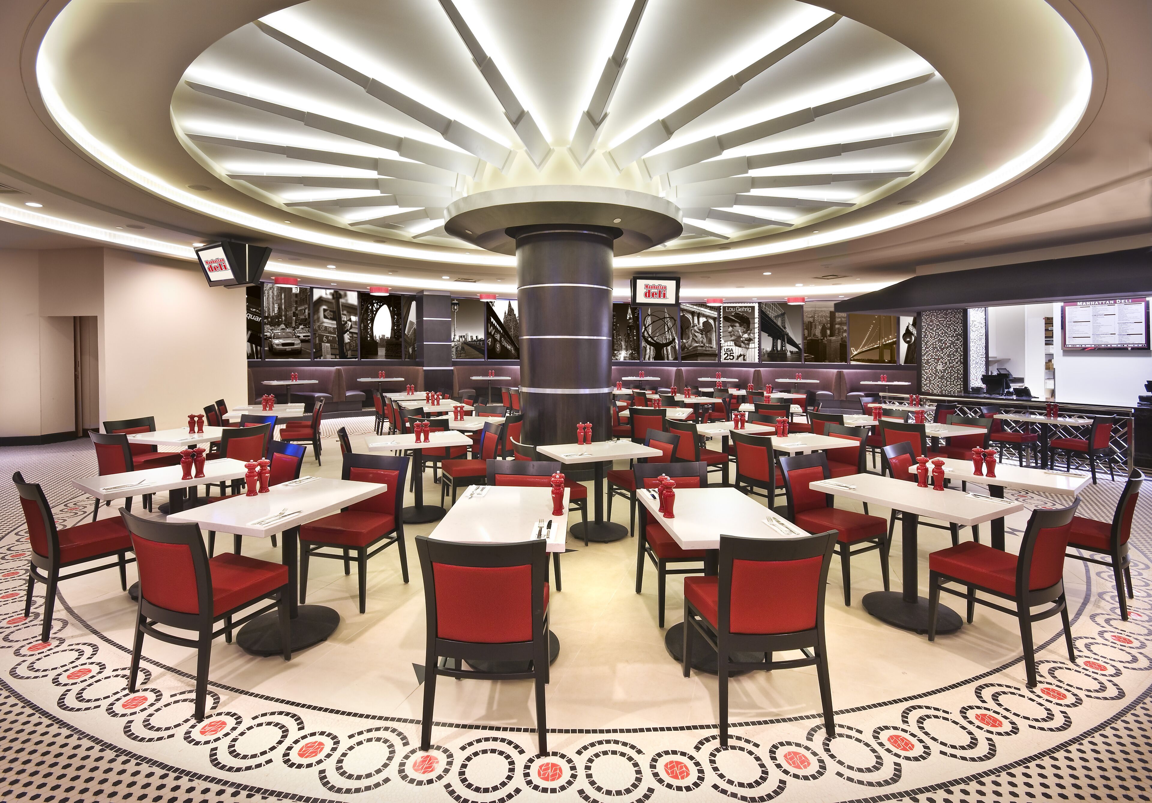 Een ruim restaurant met meerdere tafels en stoelen, een centrale pilaar en een vloer met patroon.