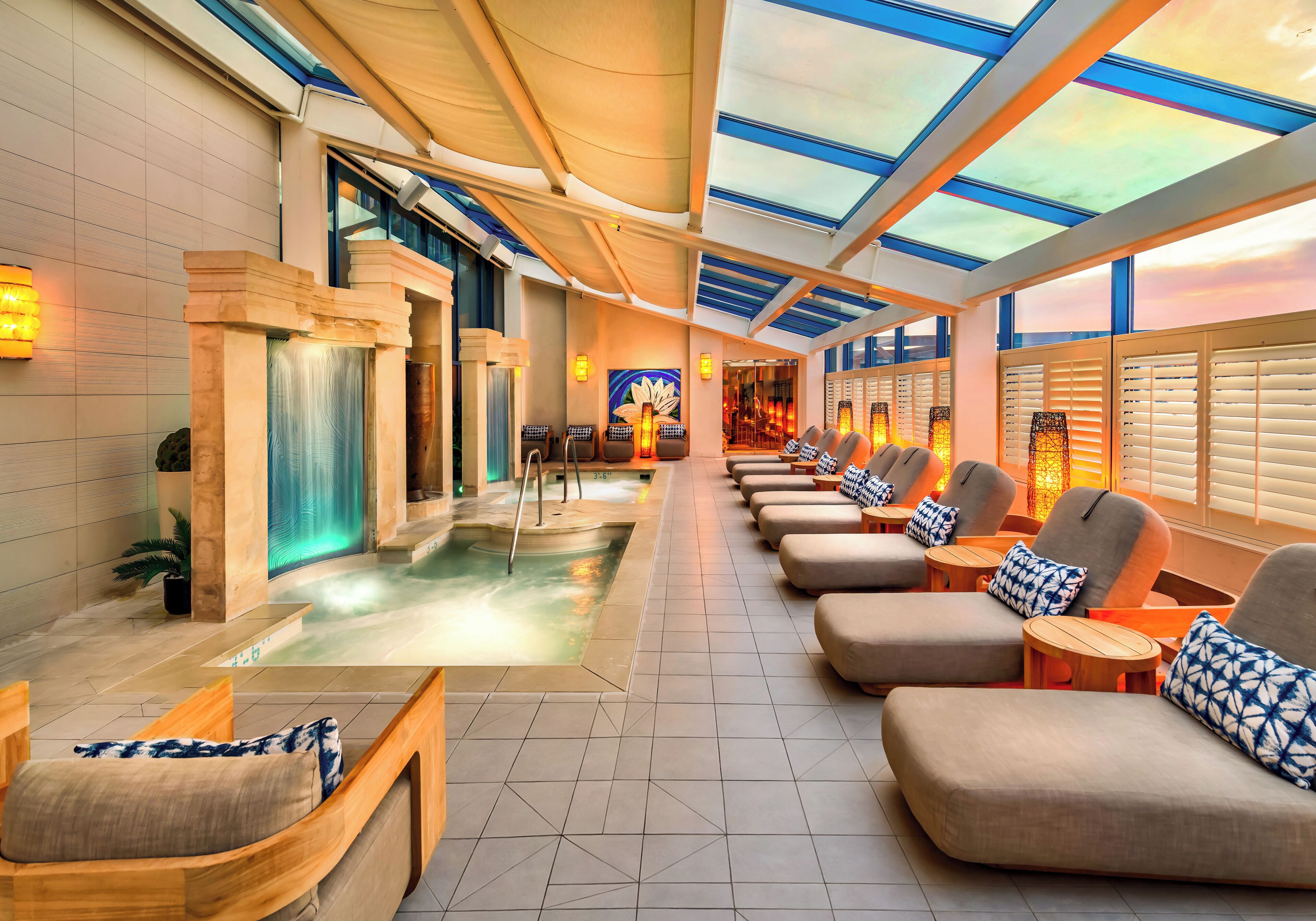 A spa area with a hot tub, seating, and a view through a glass ceiling.