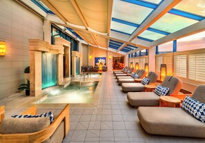 A spa area with a hot tub, seating, and a view through a glass ceiling.