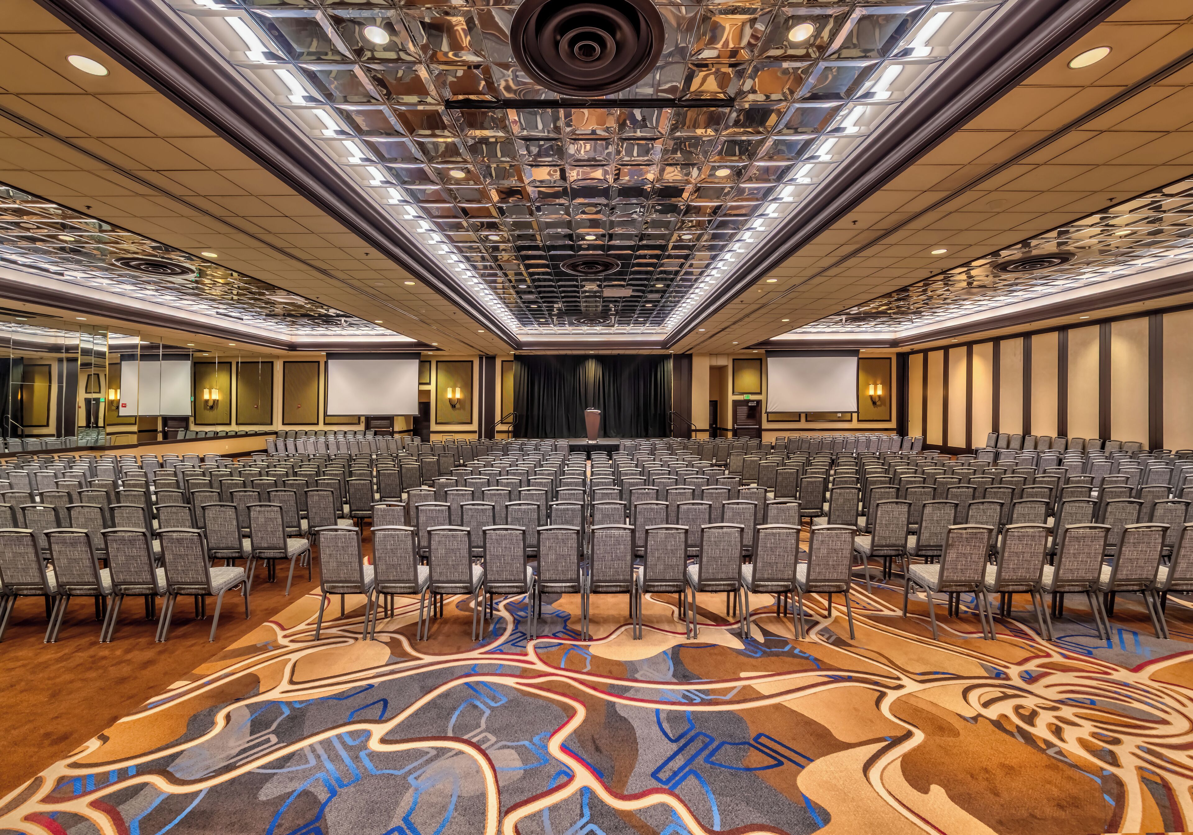 A large conference room with rows of chairs, a patterned carpet, and a ceiling with a central light fixture.