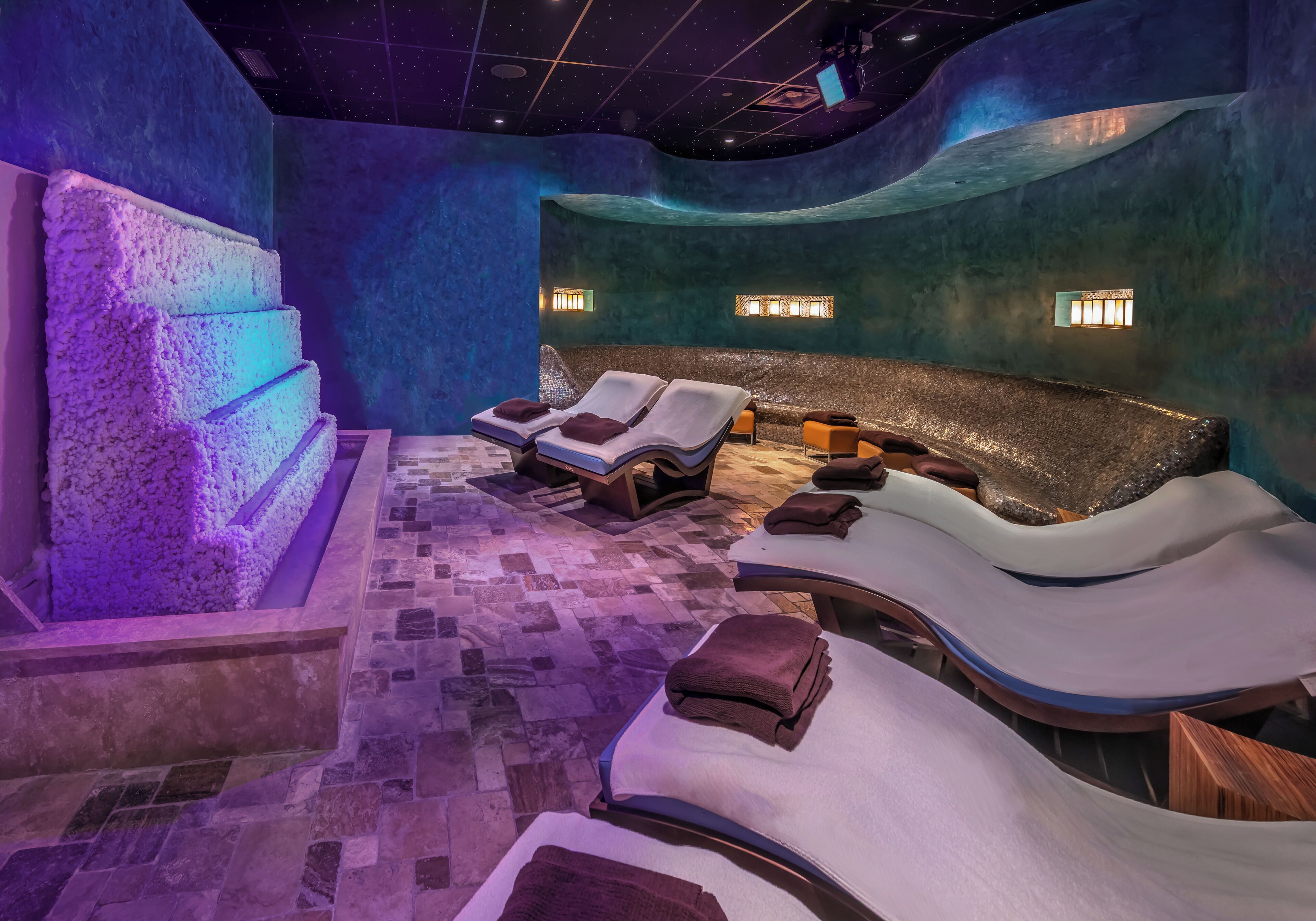 Un spa doté de fauteuils inclinables, d’un mur en pierre et d’un plafond étoilé.