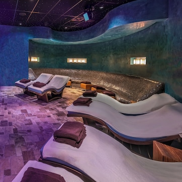 A spa with reclining chairs, a stone wall, and a starry ceiling.