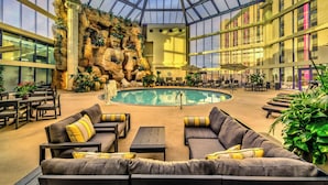 A spacious indoor area with a pool, seating, and a rock wall.