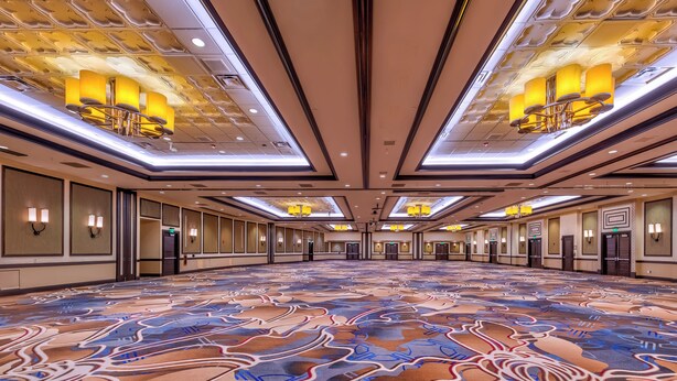 A spacious hotel lobby with a patterned carpet, modern chandeliers, and a high ceiling. - Atlantis Casino Resort Spa (Reno)