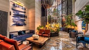 A spacious lobby with a modern design, featuring a large abstract painting, comfortable seating, and a unique hanging light fixture.