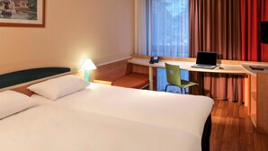 A hotel room with a bed, a desk with a laptop, a phone, and a chair. - ibis Bremen City Hotel (Bremen)