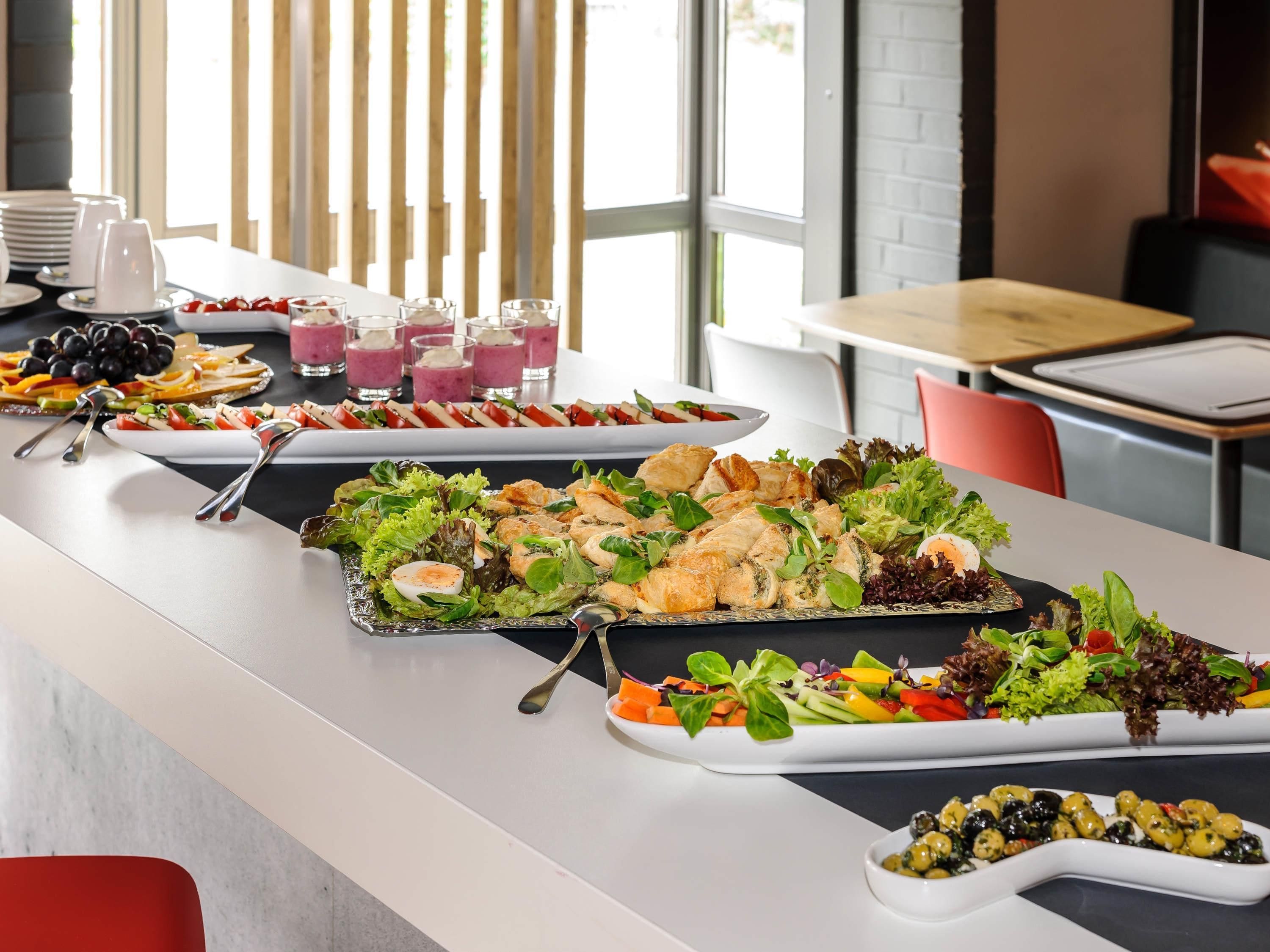 A buffet table with various dishes, including salads, meats, and a fruit platter.