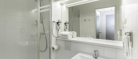A modern bathroom with a glass-enclosed shower, a white sink, and a large mirror.