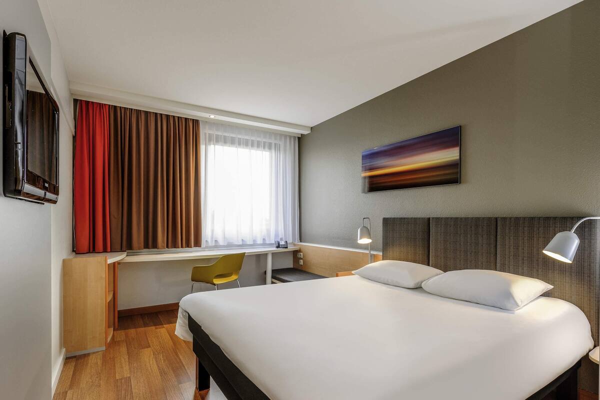 Une chambre d’hôtel équipée d’un lit, d’un bureau, d’une chaise et d’un téléviseur.