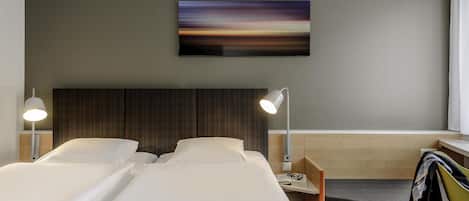 A hotel room with two beds, a desk, a chair, a TV, and a painting on the wall.