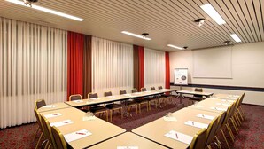 A conference room with a long table, chairs, a projector screen, and a whiteboard. - ibis Bremen City Hotel (Bremen)