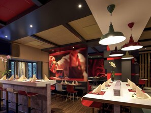 Un intérieur de restaurant moderne, avec un bar, des tables et une décoration aux couleurs rouge et blanche.