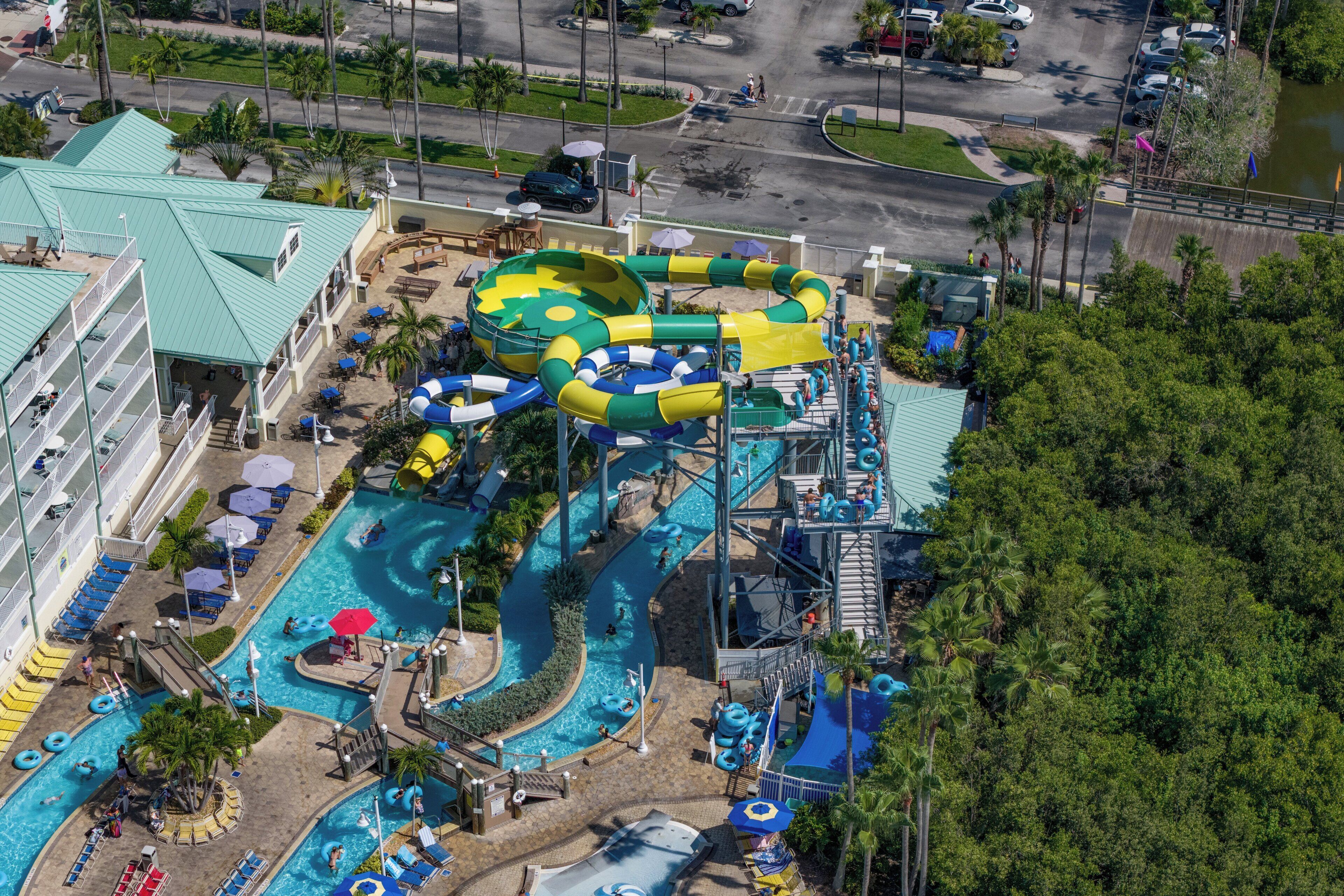 Un parc aquatique doté de nombreux toboggans et de plusieurs piscines, entouré de palmiers et d’un hôtel.