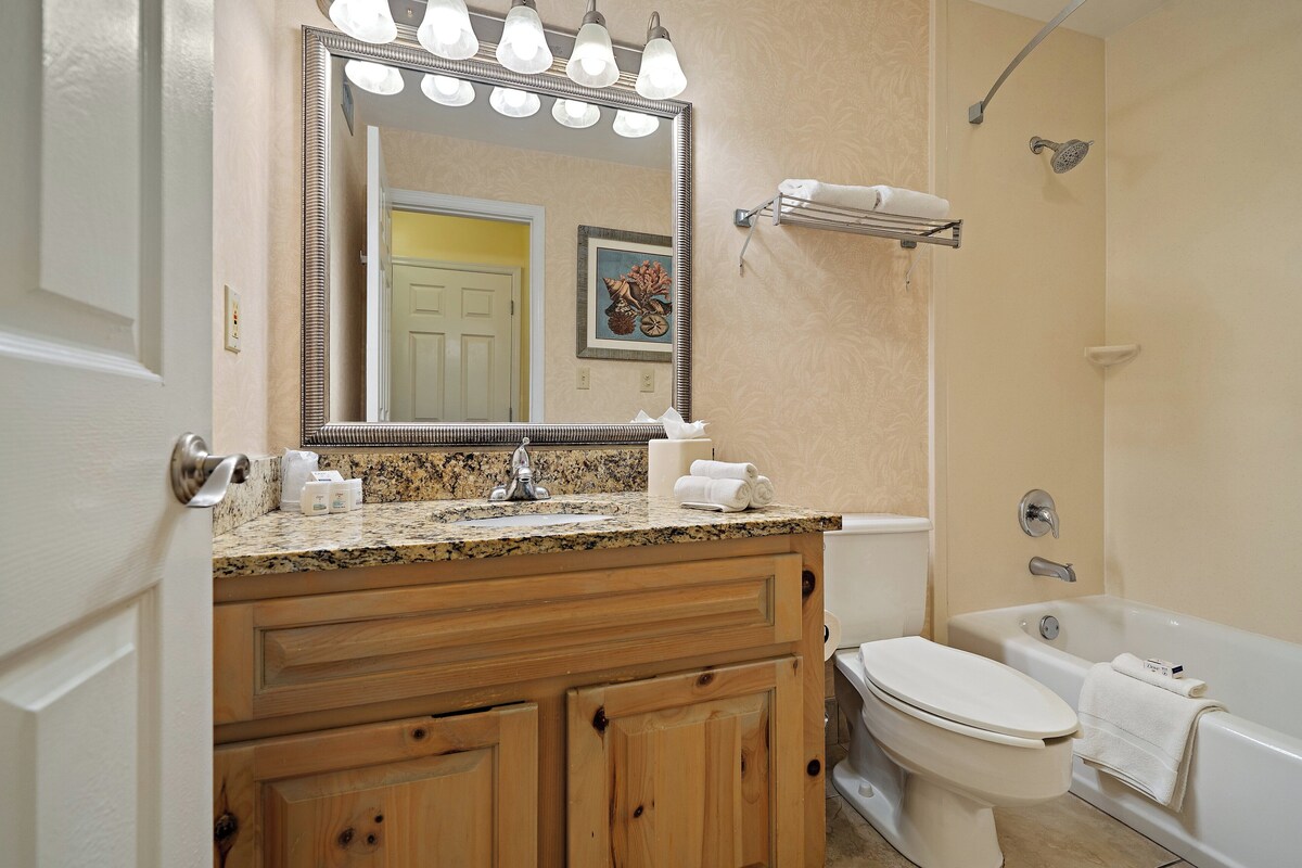 A bathroom with a wooden vanity, a sink, a toilet, and a bathtub.
