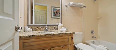 Un baño con tocador de madera, lavamanos, inodoro y bañera.