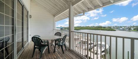 A covered outdoor area with a wooden deck, a table with chairs, and a view of a river and distant buildings.