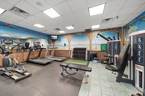 Un gimnasio con cintas de correr, elípticas y equipos de levantamiento de pesas.