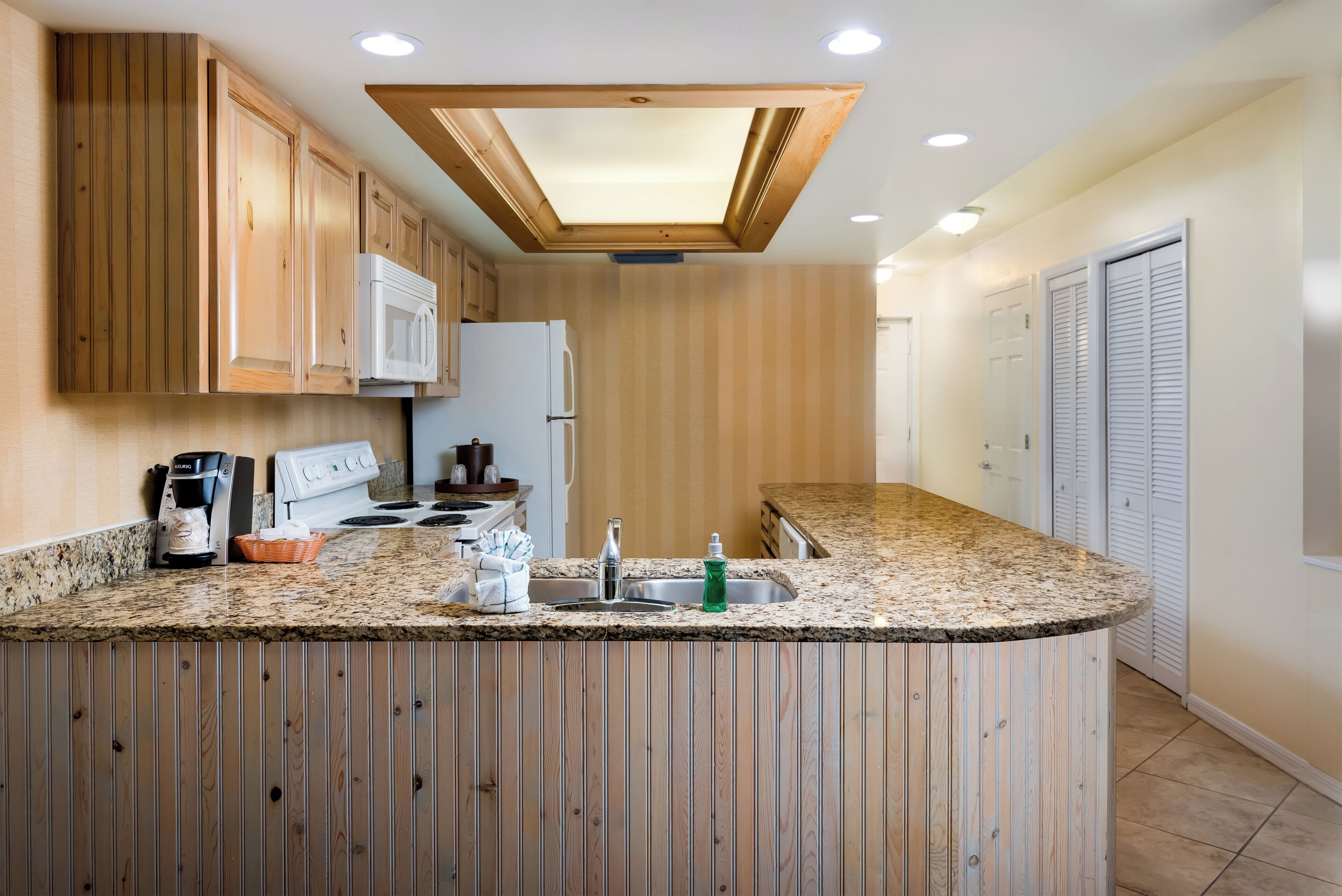 A kitchen with wooden cabinets, a white refrigerator, a stove, and a granite countertop.