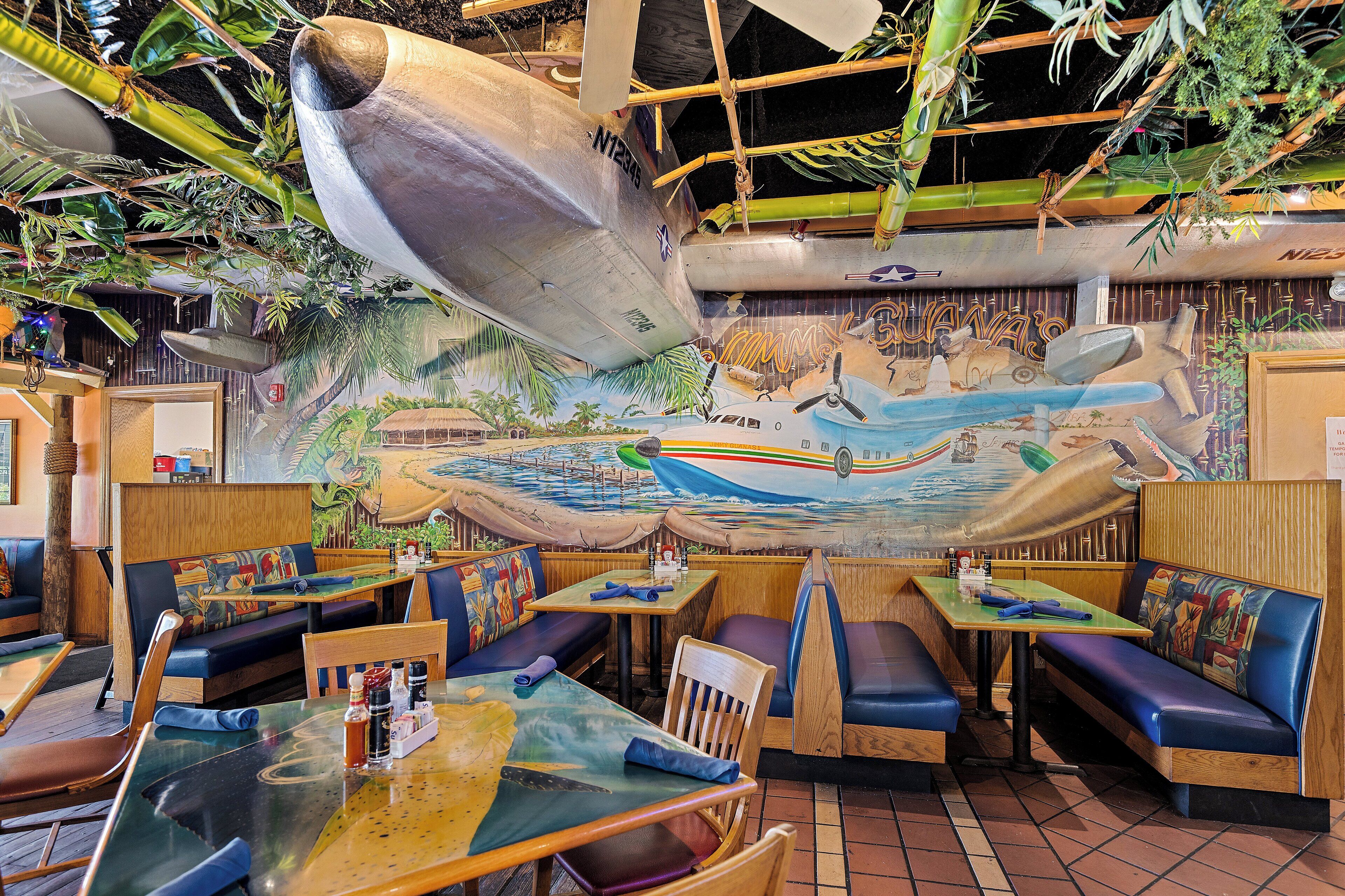 A restaurant with nautical-themed murals, wooden booths, and tables with blue cushions.