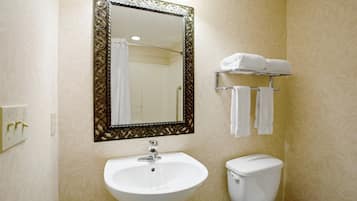A bathroom with a white sink, a toilet, a mirror with an ornate frame, and a towel rack with towels.
